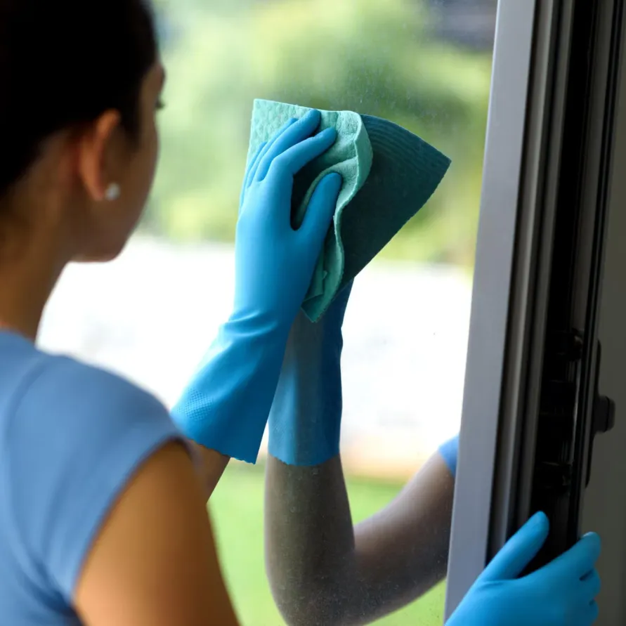 Lächelnde Reinigungskraft bei der Arbeit am Fenster